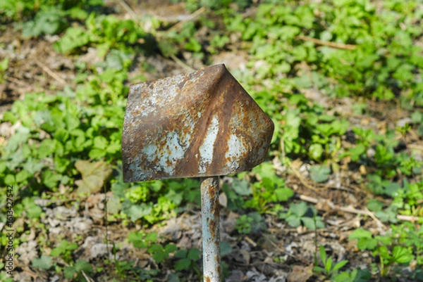 Fototapeta A bent and rusty metal sign stuck into the ground. A template with a blank old sign.