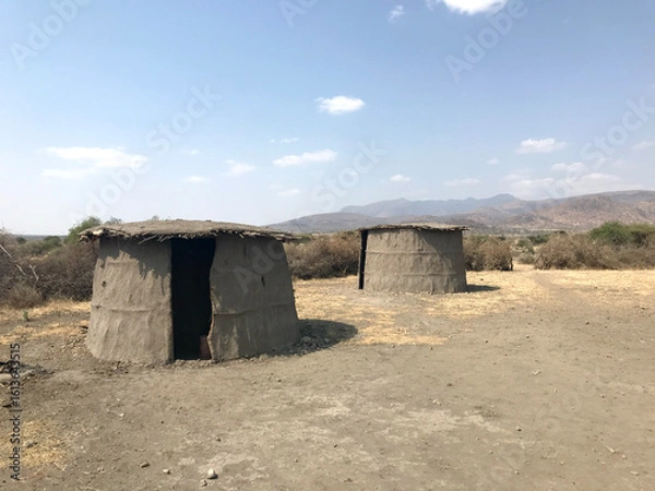 Fototapeta Traditional Maasai huts in a remote, arid African savanna under a vast, cloudless sky, symbolizing traditional nomadic life in East Africa.