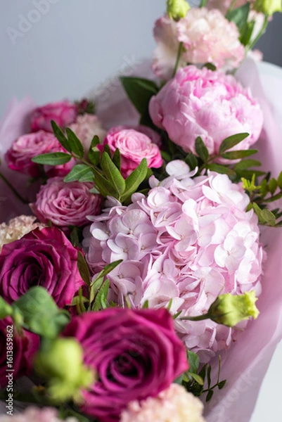 Obraz Pink bouquet of roses, peonies, eustoma and hydrangea on a light background. Festive professional flower arrangement in soft pink tissue paper. Romantic bouquet of buds and greenery close-up