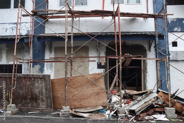 Fototapeta The atmosphere of the building yard is messy with building remains that have been collected carelessly, it appears that the scaffolding is still installed in front of the renovated building