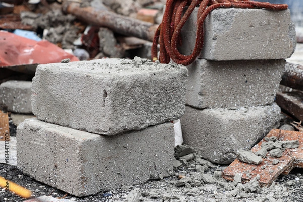 Fototapeta Several white bricks are stacked among the fragments and chunks of the remaining building, a red rope made of cloth is visible on top of the bricks