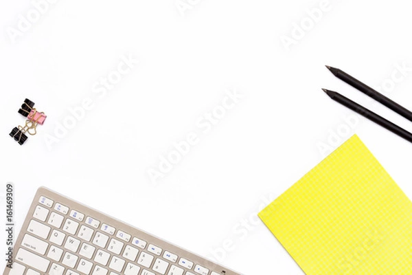 Obraz computer keyboard, a yellow pad, two black pencil and clips for paper on white background. Minimal business concept of working place in the office.