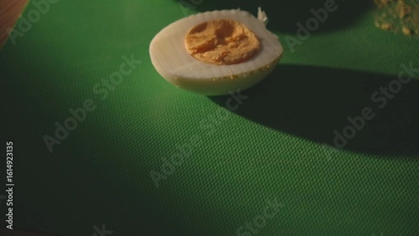 Fototapeta Egg halves with yolk on green cutting board with copyspace