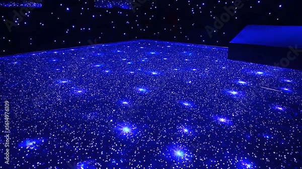 Fototapeta Dark blue floor with numerous tiny blue lights creating a starry night effect.  A slightly elevated dark object is visible in the upper right