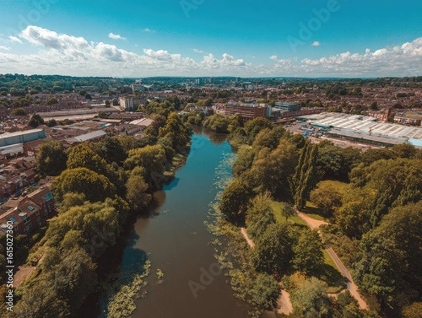 Fototapeta Aerial view of a river winding through a green, urban landscape on a sunny day
