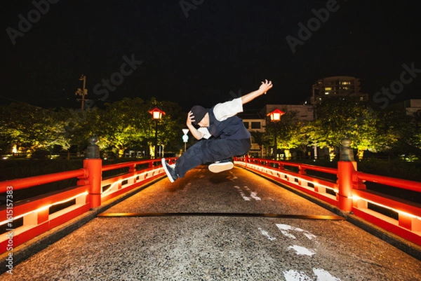 Obraz ライトアップされた和風の橋でブレイクダンスジャンプを披露する若い男性