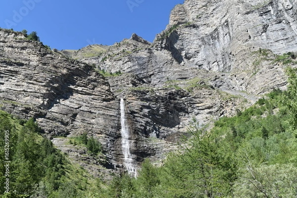Obraz Cascade au milieu des montagnes, située au cœur du Parc National des Écrins, lors d'un journée ensoleillée.