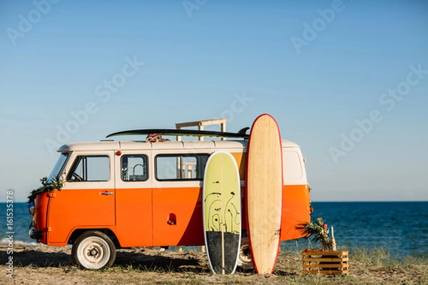 Obraz Autobus z deską surfingową na dachu jest zaparkowany w pobliżu plaży