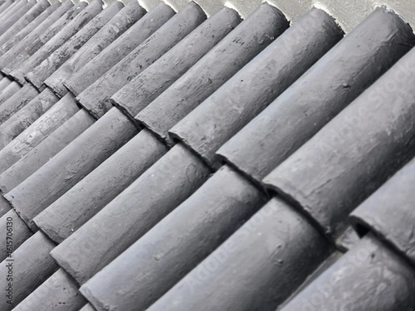 Obraz close up view of dark, textured roof tiles arranged in pattern, showcasing their unique design and material. image captures essence of architectural detail and craftsmanship