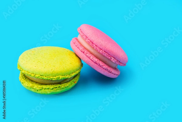 Obraz Mixed of colorful macaroni or pasta cake on a blue background. Sweet and colorful french macarons. Two multi-colored green and pink macaroons. Culinary and cooking concept, styling food.