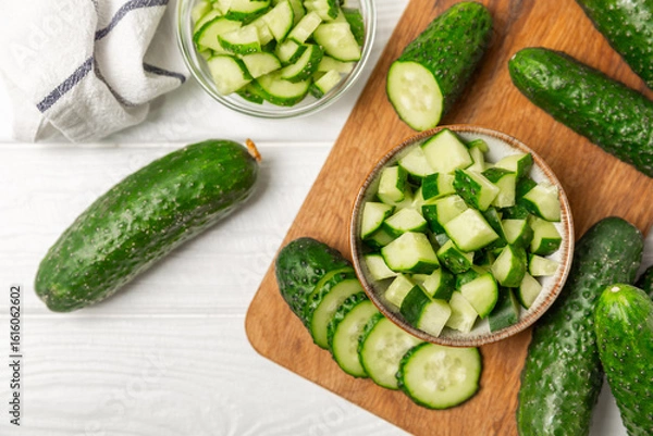 Obraz Cucumber on wooden background. Slice of cucumber on background. Fresh organic green cucumbers gherkin. Vegan. Salad ingredient. Farm vegetables. Cut vegetables with knife. Space for text. Copy space