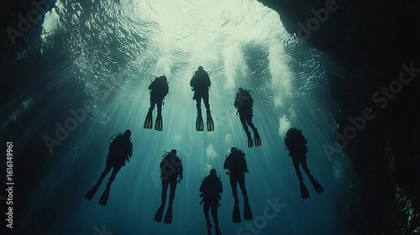 Fototapeta Group of divers exploring a mysterious cave underwater surrounded by unique rock formations and life