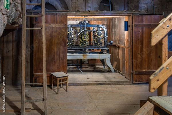 Fototapeta Historic tower clock mechanism in a wooden case mounted on wooden planks, surrounded by solid walls and ladders – mechanical clockwork on a wooden pedestal in an airy tower chapel