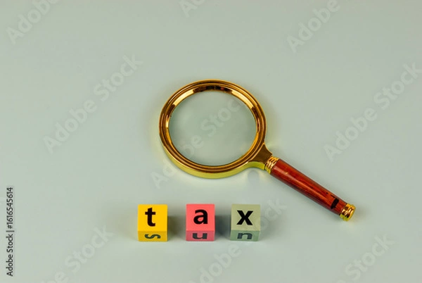 Fototapeta Tax time scrutinized. A magnifying glass focuses on the word "tax.