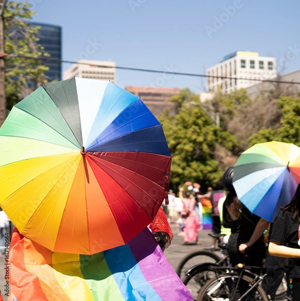 Obraz People holding rainbow umbrellas and pride flag at LGBTQ street parade