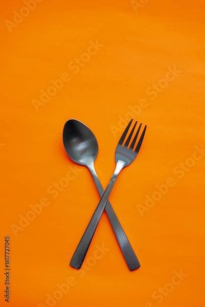 Fototapeta Black Spoon and Fork Crossed on Orange Background