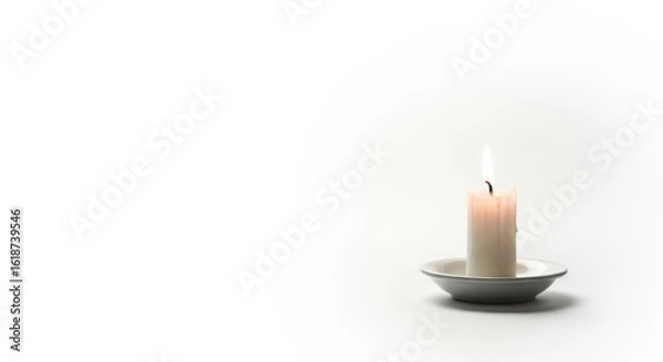 Obraz Simple white candle burning with soft flame on ceramic plate against clean white background. Perfect for meditation, relaxation, spa, memorial, and peaceful ambiance concepts.