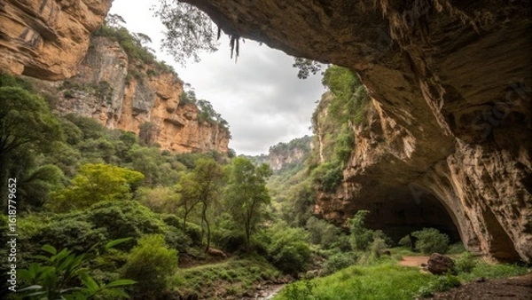 Obraz Explore a hidden natural wonder a lush gorge with towering cliffs and a mysterious cave entrance