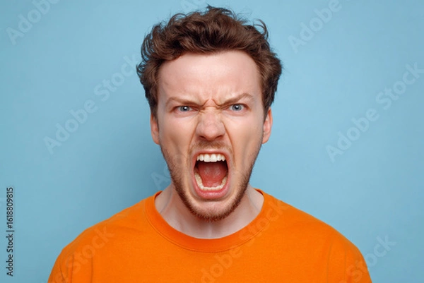 Fototapeta A man with an angry expression shouts with his mouth wide open