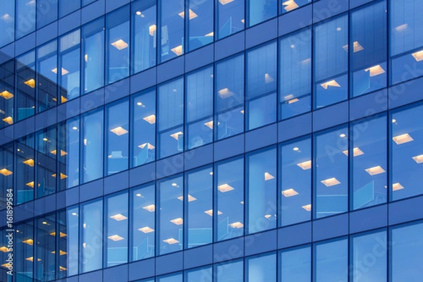 Fototapeta office building windows with inner artificial lamplight in blue color tone