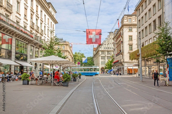 Fototapeta Zurich shopping street Bahnhofstrasse with tram and swiss flag