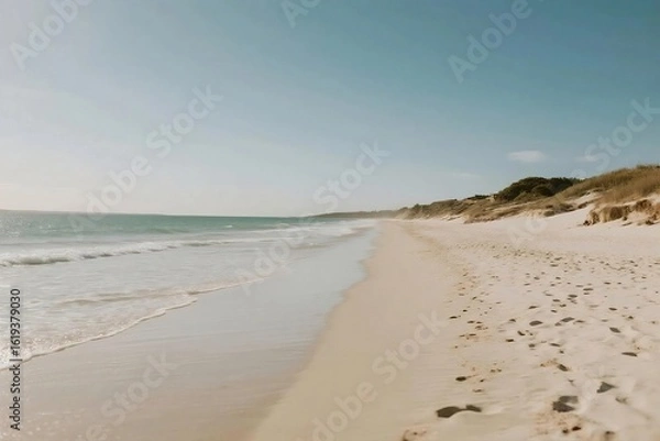 Fototapeta Wide Sandy Beach with Gentle Waves and Dunes under Clear Blue Sky