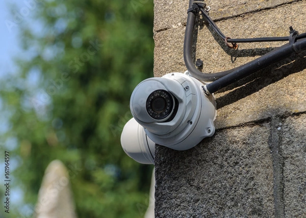 Fototapeta white CCTV camera on a stone wall