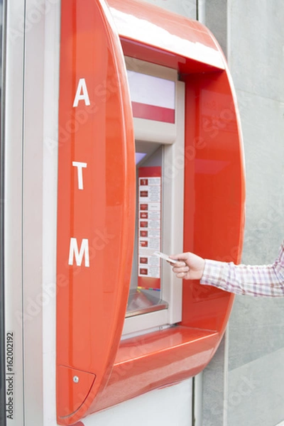 Fototapeta Hand of a man with a credit card, using an ATM. Man using an atm machine with his credit card.