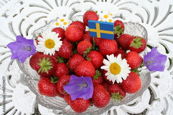 Fototapeta Sweet Swedish strawberries for Midsummer  with Swedish flag and flowers on top