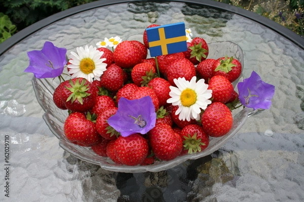 Fototapeta Sweet Swedish strawberries for Midsummer with flag and flowers on top