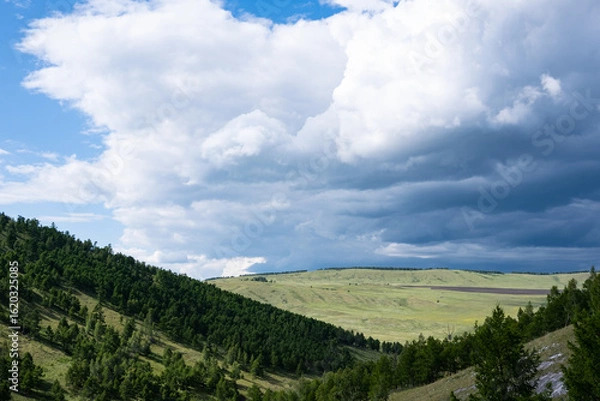 Obraz A large cloud finds a hilly valley