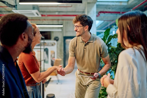 Fototapeta Business team welcoming a new employee with a handshake in a modern office, fostering collaboration and building strong connections