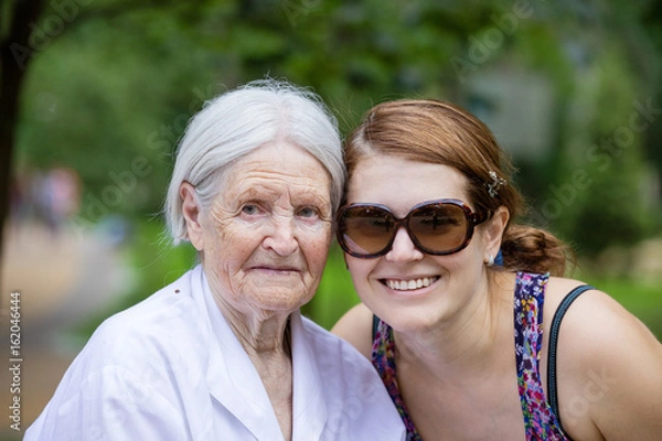 Fototapeta Adult granddaughter and senior grandmother smiling outdoors