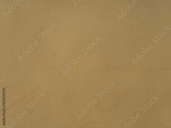 Fototapeta Dark yellow wall texture with small cracks and weathered paint. Close-up of an aged building surface, theme and concept for architectural, urban, and design backgrounds