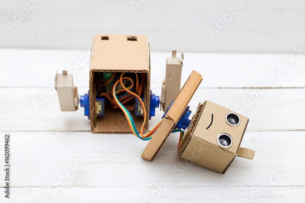 Obraz  broken robot with hands on the white wooden background