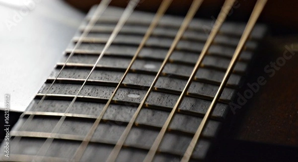 Obraz A black guitar up close with the strings in the background