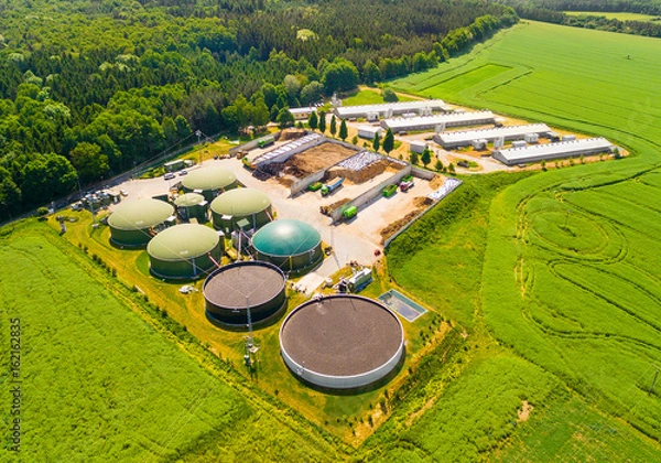 Fototapeta Widok lotniczy nad fabryką i gospodarstwem biogazowym na zielonych polach. Energia odnawialna z biomasy. Współczesne rolnictwo w Czechach i Unii Europejskiej.