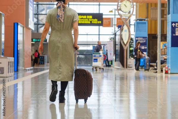 Obraz 空港で手荷物を押して歩く女性の後姿　旅行客　観光客