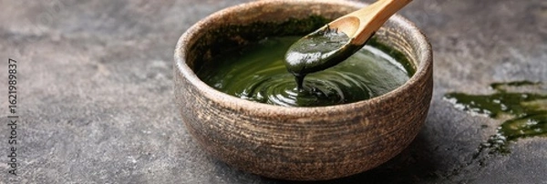 Fototapeta Mixing Green Tea Facial Mask in a Ceramic Bowl With Natural Textures and Clean Side for Skincare Routine Enhancement