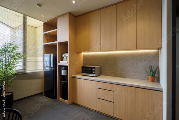 Fototapeta Modern office pantry with wooden cabinets, microwave, and water dispenser. A minimalist and functional kitchen area for a contemporary workspace.