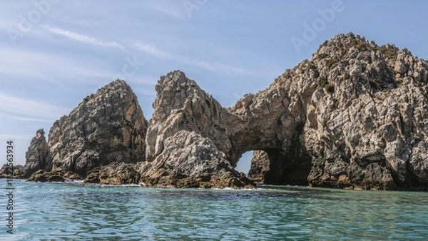Fototapeta Gigantic textured granite formations lining a scenic pink coast, with large stones near a serene seaside setting in summer.