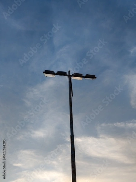 Fototapeta Close up of a street light against a blue sky with some wispy clouds, minimal, vertical shot,4k