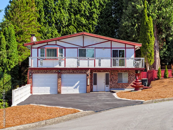 Obraz Family residential house with double garage and tall trees on the back yard
