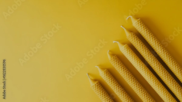 Obraz Aesthetic arrangement of natural beeswax candles on a yellow background