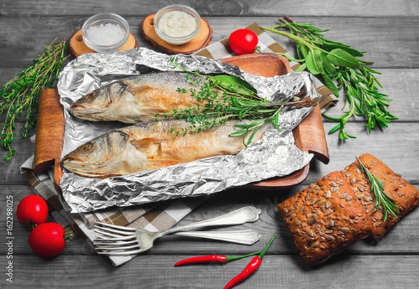 Obraz Grilled whole trout on an aluminum foil on a wooden log