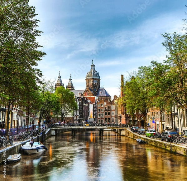 Fototapeta The most famous canals and embankments of Amsterdam city during sunset. General view of the cityscape and traditional Netherlands architecture.