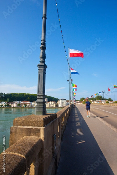 Fototapeta Mężczyzna uprawiający sport na zewnątrz, biegnący szybko wzdłuż mostu. A man exercising outside, running fast along a bridge.