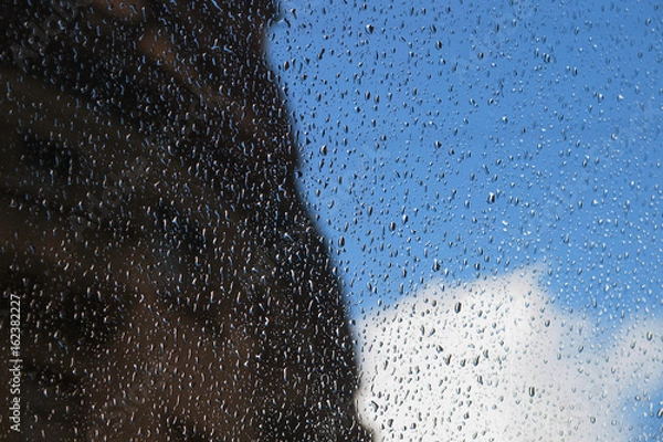 Fototapeta Drops of rain on the window, sky, cloud and silhouette of the building