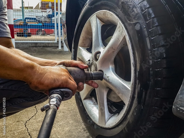 Obraz screwing car tire with pneumatic wrench