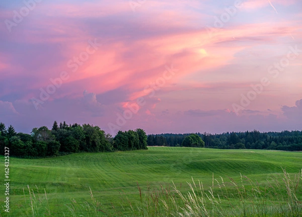 Fototapeta Grüne Landschaft im Voralpenland mit buntem Himmel und rosa Wolken bei einem wunderschönen Sonnenuntergang, Oberbayern, Bayern, Deutschland, Europa